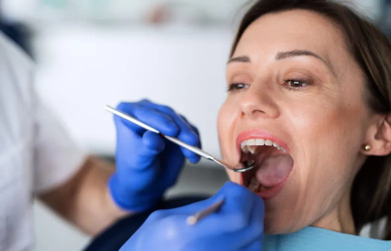 mujer con las manos de los dentistas en la boca